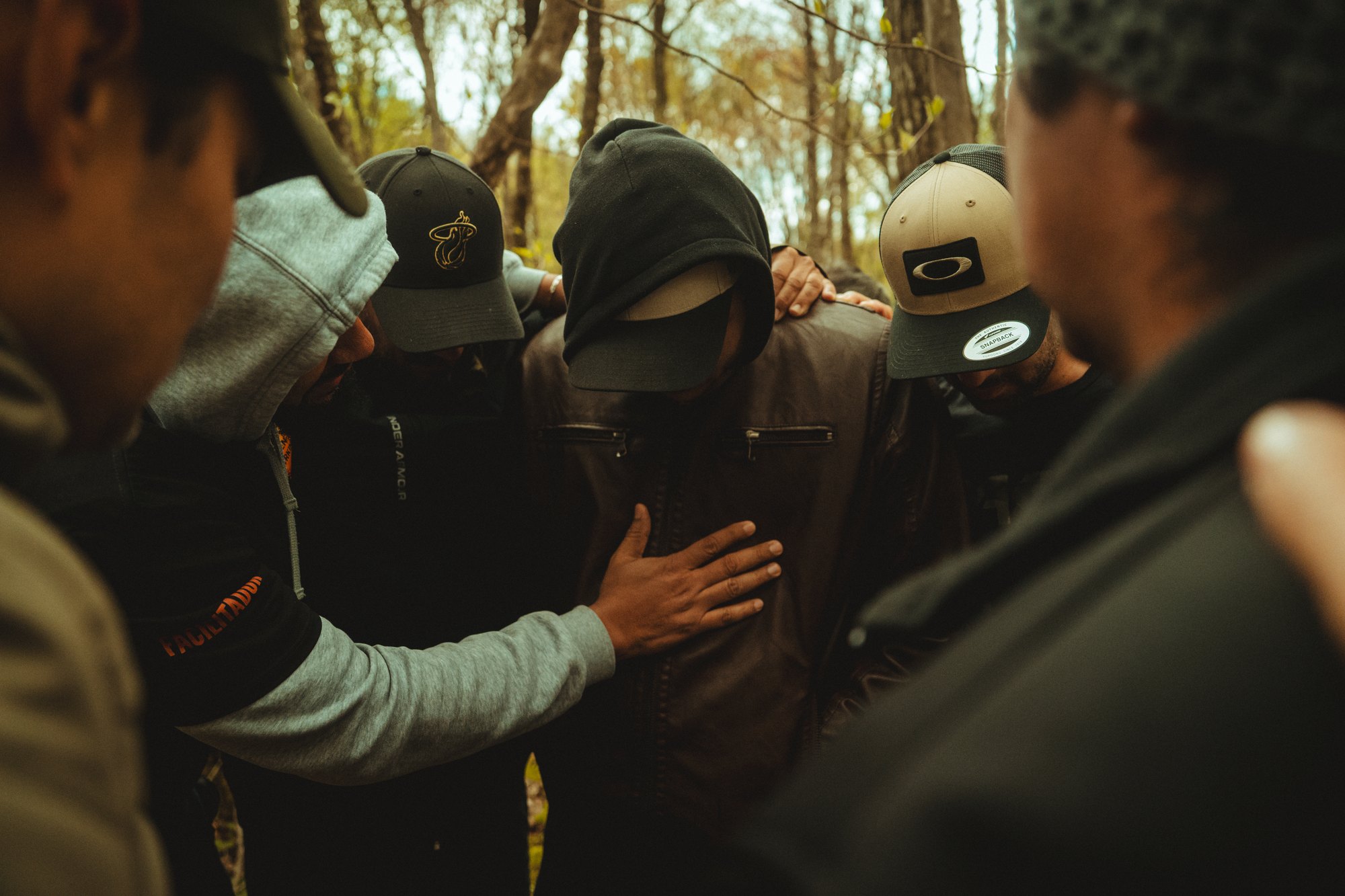 Hombres en círculo orando en el bosque durante el retiro